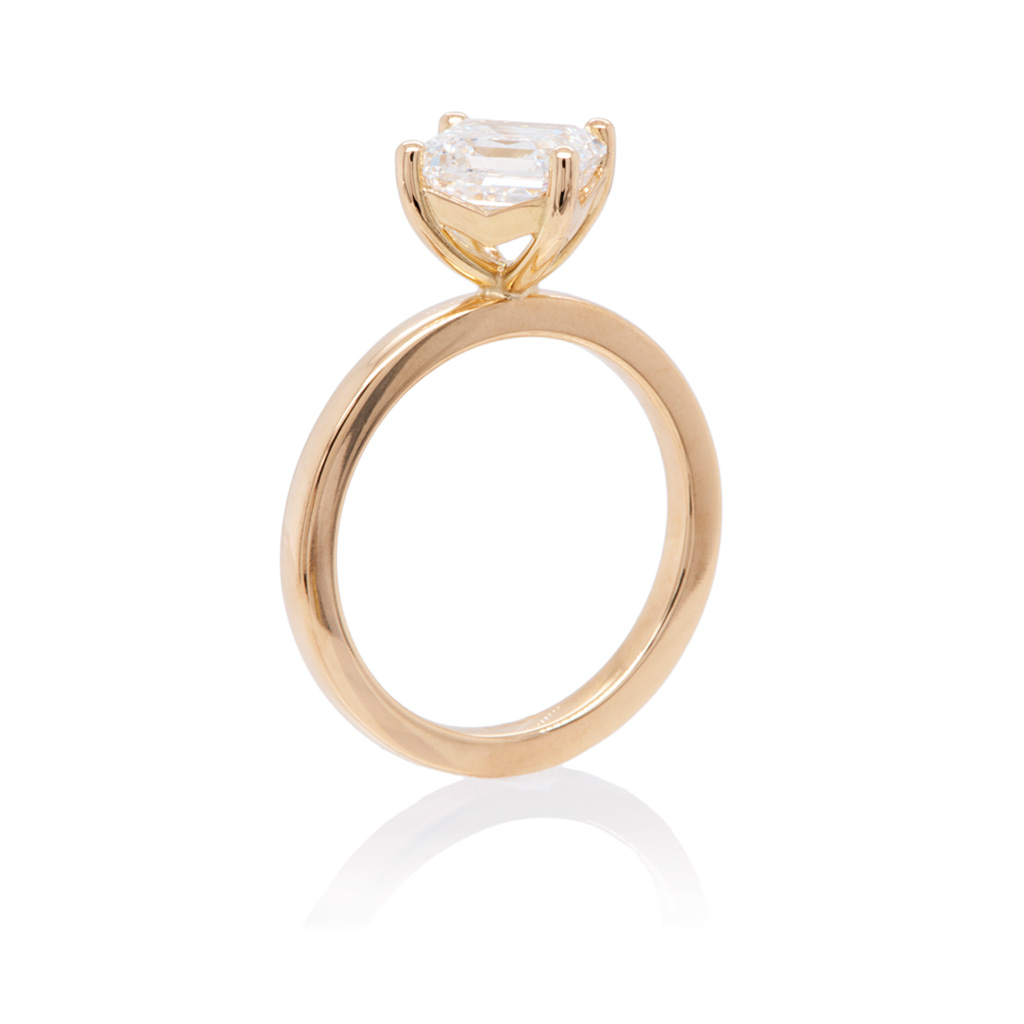 Asscher cut diamond solitaire ring in a 4-prong kite setting standing upright on a white background