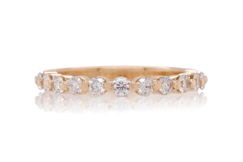 A diamond eternity ring in yellow gold on a white background. The diamonds are arranged in a single row with a shared claw setting.