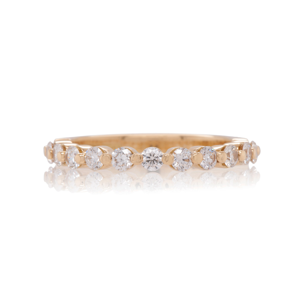 A diamond eternity ring in yellow gold on a white background. The diamonds are arranged in a single row with a shared claw setting.